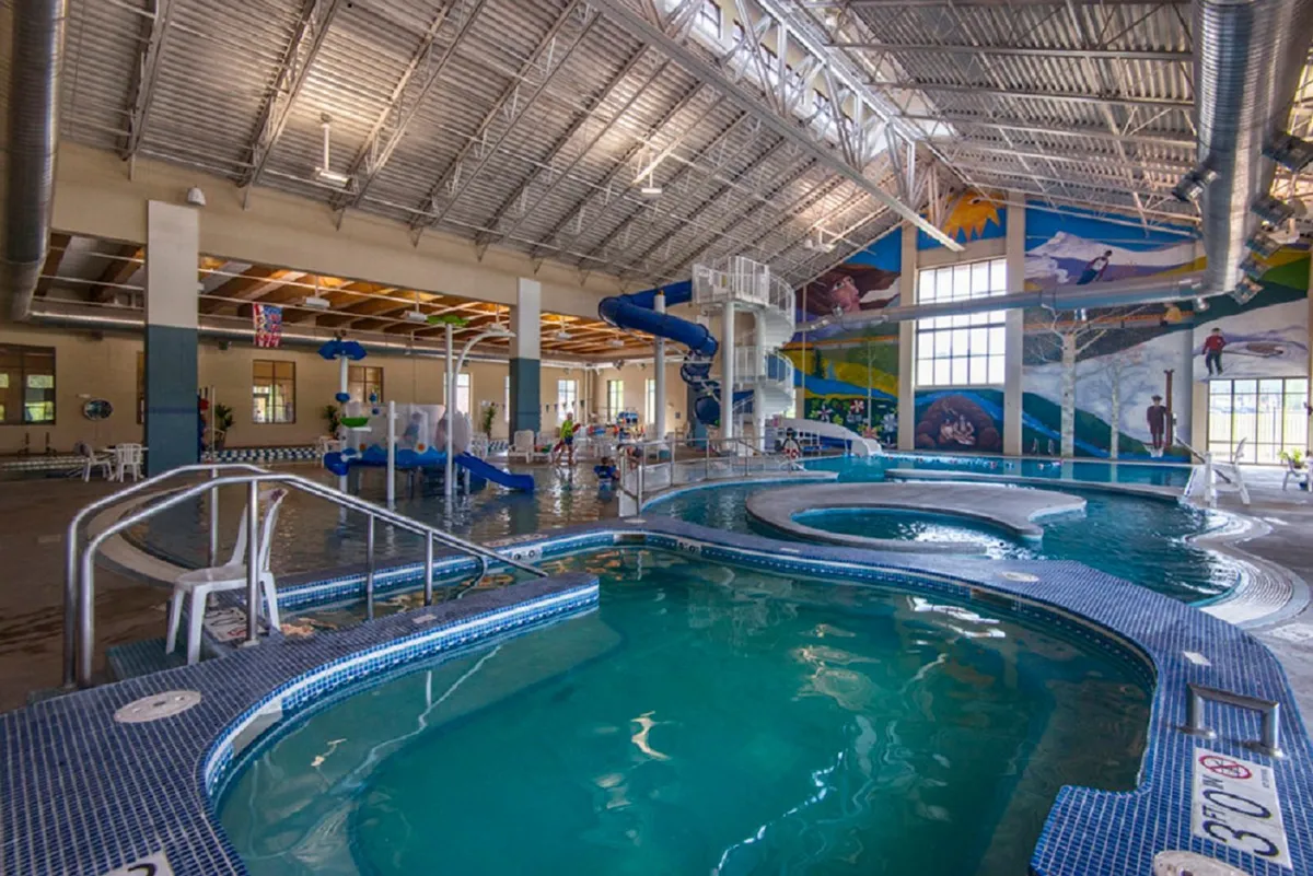 This vibrant interior image captures a lively pool area with colorful water slides, children enthusiastically playing, and bright murals on the walls. The atmosphere is energetic and joyful, embodying the spirit of family-friendly recreation.